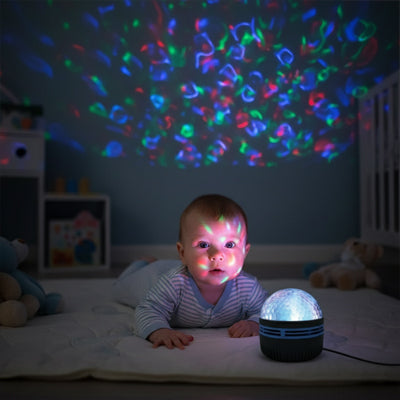 Veilleuse projection colorée illuminant le visage d'un bébé allongé sur un tapis
