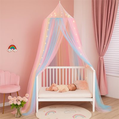 Ciel de lit arc-en-ciel et guirlandes au-dessus d'un lit bébé avec tout-petit endormi