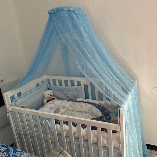 Ciel de lit bébé bleu au-dessus d'un berceau avec peluche