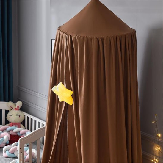 Ciel de lit bébé marron avec étoile jaune installé à côté d'un berceau