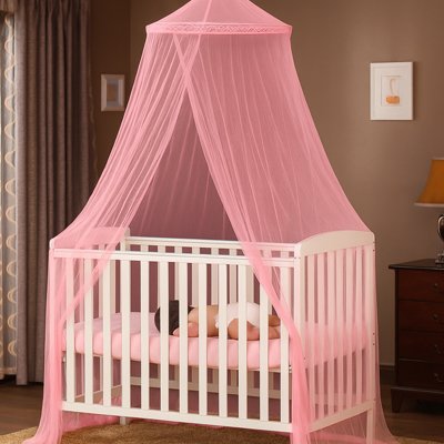 Ciel de lit rose léger enveloppant un lit bébé blanc et un nourrisson