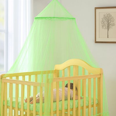 Ciel de lit vert fin protégeant un bébé endormi dans son lit en bois