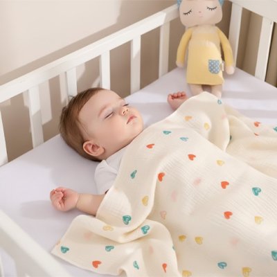Couverture bébé à motif cœurs sur un nourrisson endormi dans son berceau