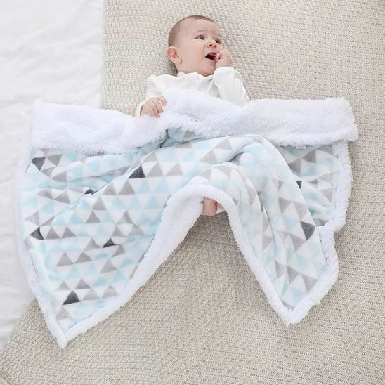 Couverture bébé triangles colorés dépliée avec nourrisson bébé allongé bras écartés