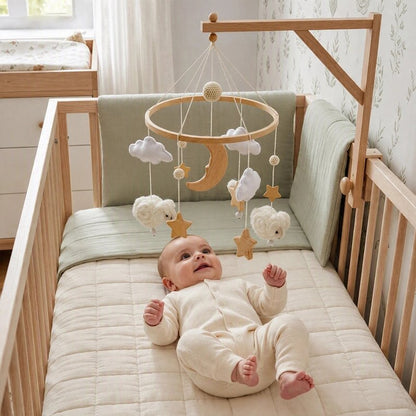 Mobile bébé avec tout-petit souriant tendant la main vers un mouton rose