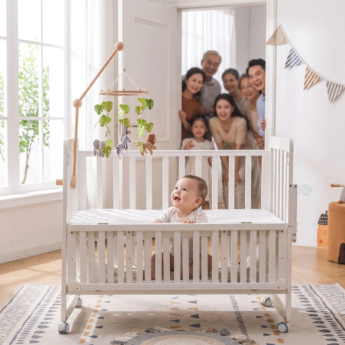 Mobile bébé jungle aux animaux suspendus avec enfant souriant et sa famille en fond