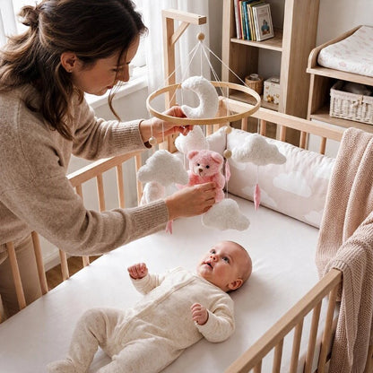 Mobile bébé ourson et nuages avec nourrisson allongé souriant et joyeux regardant les éléments suspendus