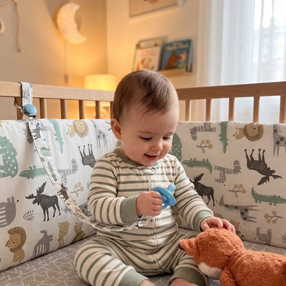 Tour de lit bébé animaux avec tout-petit  assit dans son lit  tenant une tétine