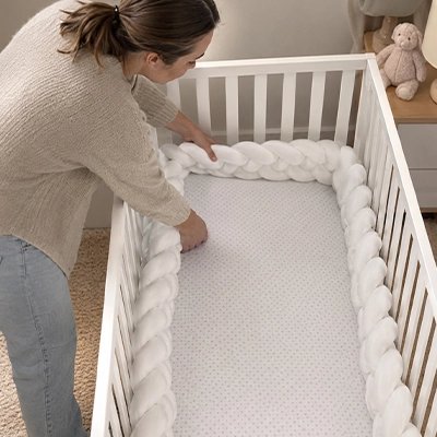 Tour de lit tressé blanc installé par une maman sur un lit pour bébé