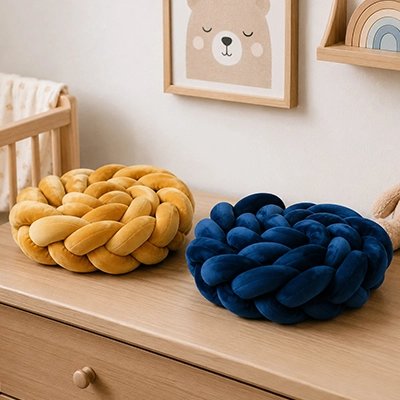 Tour de lit tressé plier en nœud couleurs moutarde et bleu marine posées sur  commode de chambre bébé