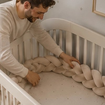Tresse de lit beige installée par papa souriant sur le lit de bébé