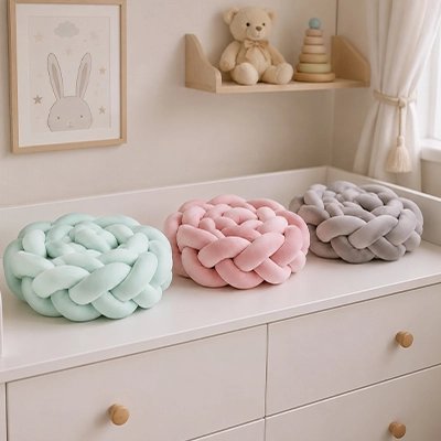 	Tresse de lit coussins nœuds décoratifs vert, rose, gris posées  sur commode
