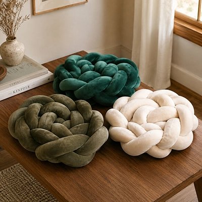 Tresse de lit en trois variantes vert, marron et crème posées sur une tablette.