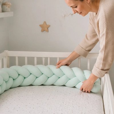 Tresse de lit verte ajustée par une maman protégeant lit enfant